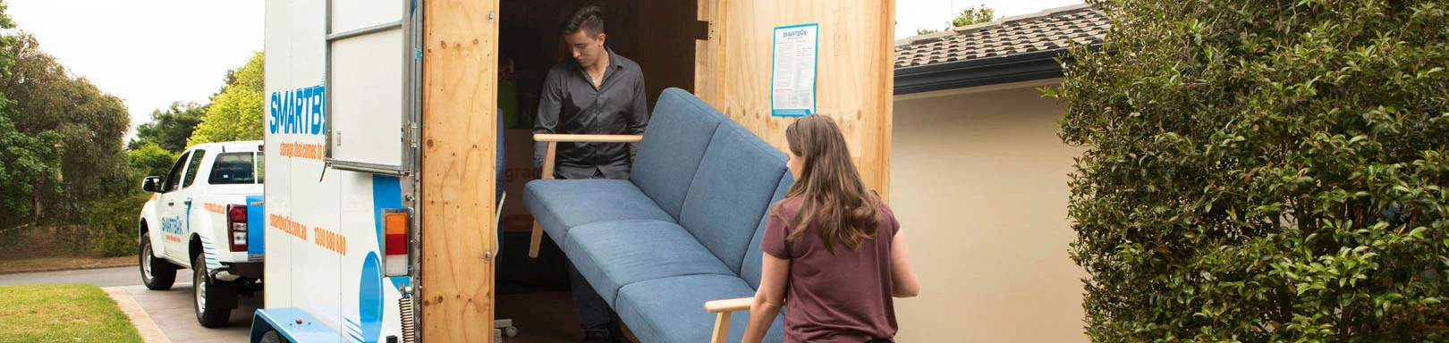 couple decluttering house, loading furniture from back of mobile storage truck