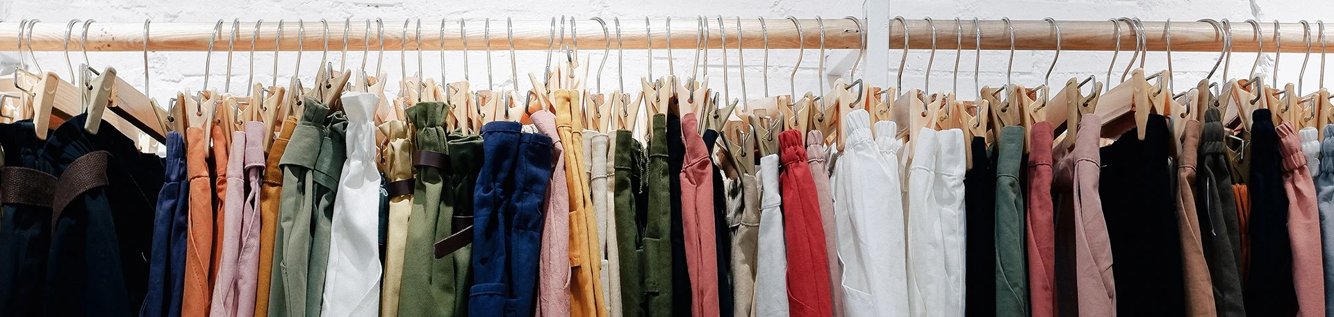 assorted clothes hanging on wooden rack
