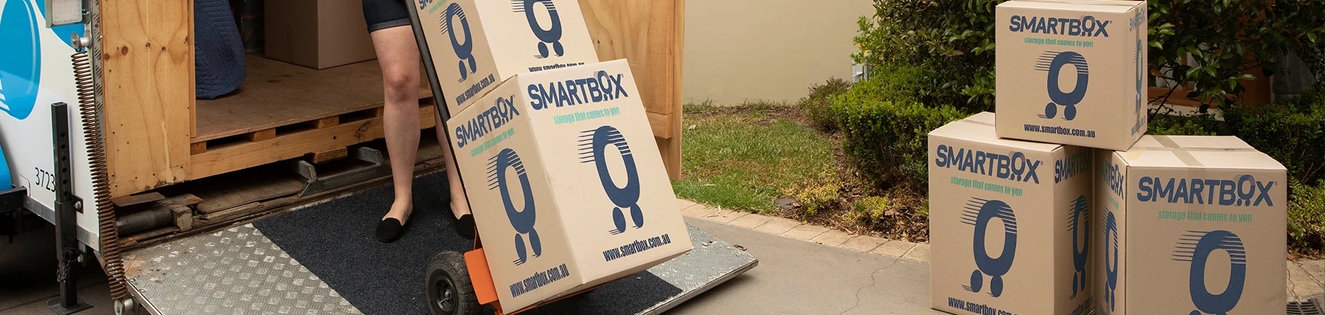 woman pulling hand truck trolley with boxes