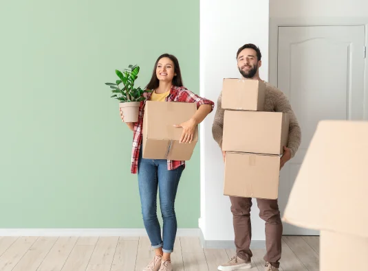 happy couple lifting boxes moving home