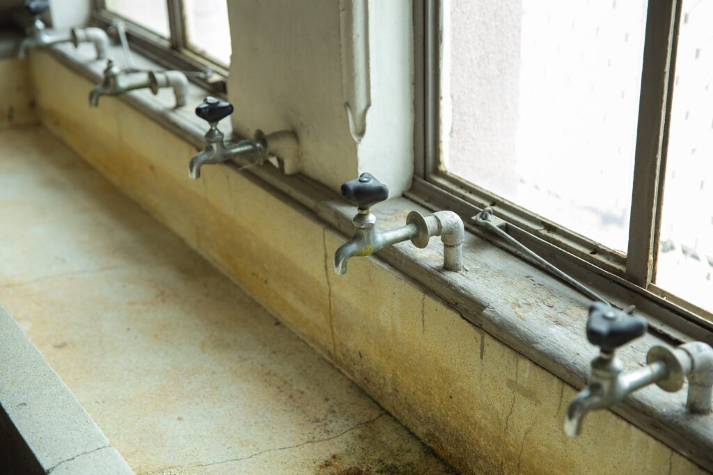 A sink with numerous faucets, exhibiting mould growth