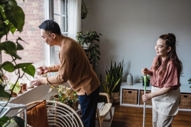 The husband is watering the plants while the wife is watching