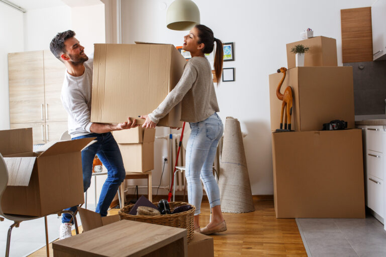 Young couple carrying big cardboard box at new home, moving house